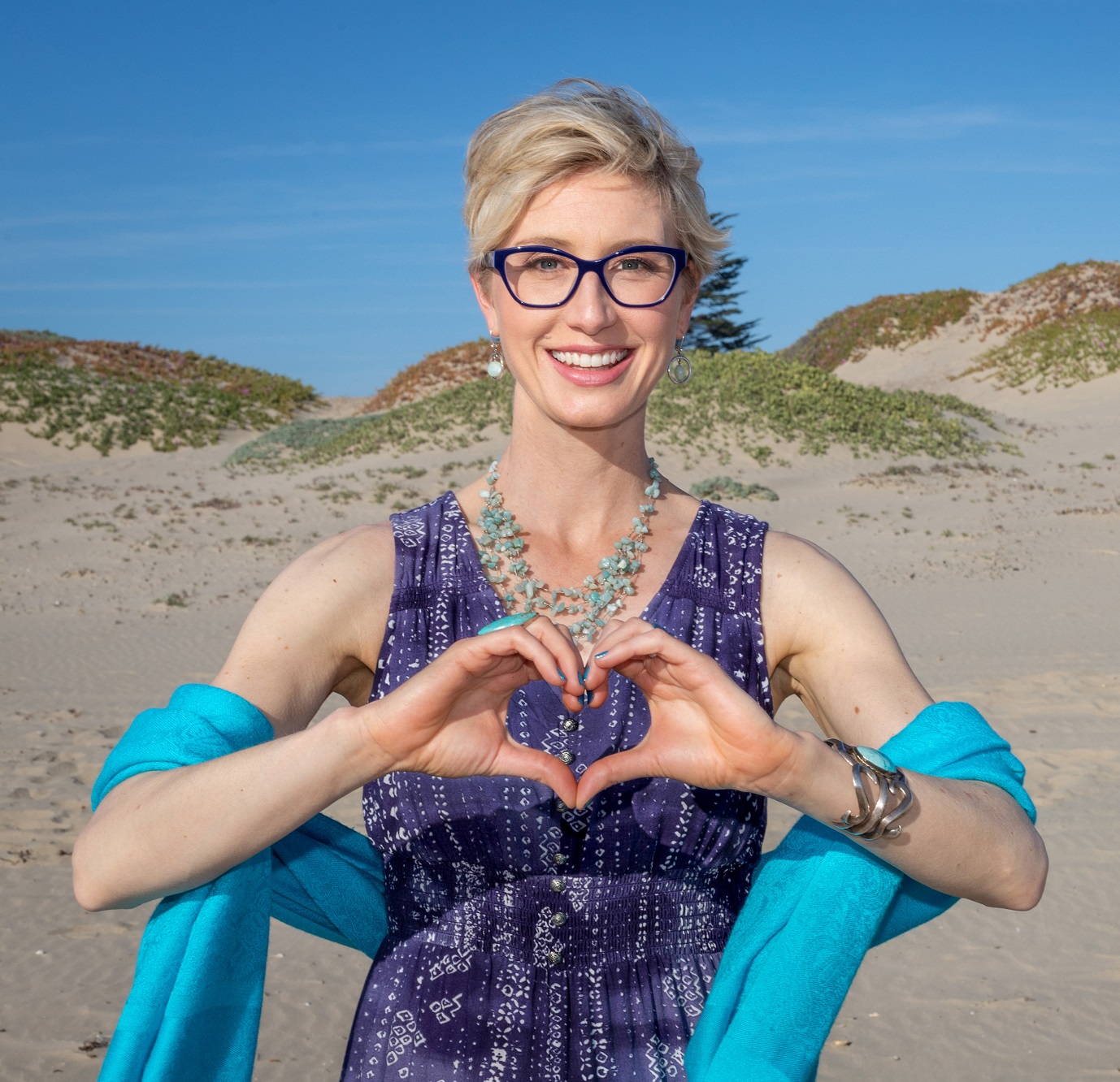 Megan Barnhard hands heart Megan Barnhard on a beach with her hands formed into a heart